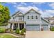 Charming two-story home with light blue siding, white trim, well-manicured landscaping, and a spacious three-car garage at 12672 Amber Star Dr, Noblesville, IN 46060