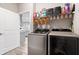 Well-organized laundry room with modern washer and dryer, shelving, and cleaning supplies near an open doorway at 13321 N White Cloud Ct, Camby, IN 46113