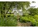 Picturesque backyard featuring a lush garden, white pergola, and a tranquil pond at 13815 Plantree Dr, Carmel, IN 46033