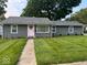 Charming single-story home featuring a well-manicured lawn and a delightful pink front door with wreath at 1398 Clinton St, Noblesville, IN 46060