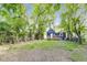 View of the backyard featuring mature trees and a charming blue house with a deck, creating a serene outdoor space at 1822 Howard St, Indianapolis, IN 46221