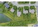 Aerial view of a property showcasing its well-manicured lawn and proximity to a serene lake, surrounded by a lush landscape at 2070 Mustang Chase Dr, Carmel, IN 46074