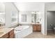 Well-lit bathroom with a soaking tub, double vanity, neutral tile, and white cabinets at 2070 Mustang Chase Dr, Carmel, IN 46074