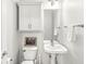 Cozy half bathroom features a pedestal sink, toilet, and vanity cabinet for convenient storage at 2070 Mustang Chase Dr, Carmel, IN 46074