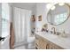 Well-lit bathroom with a tub and shower, a stylish wood vanity, a round mirror, and modern fixtures at 3215 N Pennsylvania St, Indianapolis, IN 46205