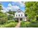 Charming white two-story home with a landscaped front yard and inviting brick walkway under a sunny, partly cloudy sky at 3215 N Pennsylvania St, Indianapolis, IN 46205