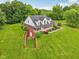 Overhead view of a red brick home with a white porch, surrounded by a well-kept lawn and trees at 3564 Clear Creek Blvd, Martinsville, IN 46151