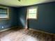 Bedroom with two windows and wood-look laminate flooring; walls painted in a dark, solid color at 409 W 3Rd St, Alexandria, IN 46001