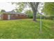 Lush green backyard featuring a brick home exterior and a mature tree providing ample shade at 412 S Norfolk St, Indianapolis, IN 46241