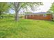 Lush green backyard featuring a brick home exterior, mature trees, and a fire pit at 412 S Norfolk St, Indianapolis, IN 46241