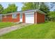View of a charming brick home with a well-kept lawn and an attached garage at 412 S Norfolk St, Indianapolis, IN 46241
