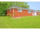 Side of a red brick home with a flower bed and lush green lawn adding to the scenery at 412 S Norfolk St, Indianapolis, IN 46241