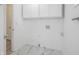 A bright laundry room with white cabinets, white walls, and marble look flooring at 412 S Norfolk St, Indianapolis, IN 46241