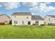 Spacious backyard featuring a patio, furniture and grill, surrounded by lush green grass and a blue sky at 4434 W Windsong Ct, New Palestine, IN 46163