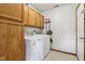 Laundry room with natural wood cabinets and white front loading washer and dryer at 4434 W Windsong Ct, New Palestine, IN 46163