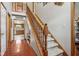 Elegant staircase with wooden railing open to a view of the kitchen at 4434 W Windsong Ct, New Palestine, IN 46163