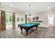 Bright game room with a billiard table and large windows showcasing the backyard garden at 4530 Chase Oak Ct, Zionsville, IN 46077