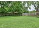 Spacious backyard featuring a large grassy area, partially enclosed by a wooden fence and mature trees at 4922 Brookville Rd, Indianapolis, IN 46201