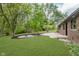 Large backyard featuring a fire pit, grass, concrete patio, and lots of mature trees at 5982 Melbourne Rd, Indianapolis, IN 46228