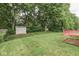 A lush backyard features a verdant lawn, mature trees, a shed, and a charming deck for outdoor enjoyment at 6010 Rocky River Dr, Indianapolis, IN 46221