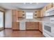 Kitchen with stainless steel sink, white appliances, and wooden cabinets at 6010 Rocky River Dr, Indianapolis, IN 46221