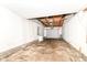 Empty garage with exposed ceiling, concrete floor, and a partially open garage door at 6238 E 43Rd St, Indianapolis, IN 46226