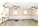 A bare, unfinished living room featuring two ceiling fans, three windows, and a brick-lined wall at 6238 E 43Rd St, Indianapolis, IN 46226