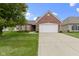Well-maintained brick home with a manicured lawn, mature tree, and attached two-car garage at 7128 Willow Pond Dr, Noblesville, IN 46062