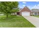 Well-maintained brick home with a manicured lawn, mature tree, and attached two-car garage at 7128 Willow Pond Dr, Noblesville, IN 46062