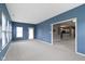 Bright living room boasts blue walls, neutral carpeting, an open floor plan, and seamless access to kitchen at 7128 Willow Pond Dr, Noblesville, IN 46062