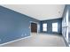 Bright living room showcasing blue walls, multiple windows with natural light, and neutral carpeting at 7128 Willow Pond Dr, Noblesville, IN 46062