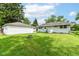 View of the backyard with a fire pit, garage, green lawn, and the back of the house at 7725 E 52Nd St, Indianapolis, IN 46226