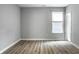 Bright bedroom features wood-look flooring, a window with blinds, and light grey walls at 9718 Haughton Ln, McCordsville, IN 46055