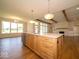 Kitchen island with a sink and stainless steel dishwasher, wooden cabinets, white countertops and pendant lights at 10586 Jacks Way, Indianapolis, IN 46234