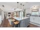 Open-concept kitchen with a gray island, pendant lights, and hardwood floors at 10673 Misty Hollow Ln, Fishers, IN 46038