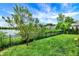 Beautifully landscaped backyard with a lake view, black metal fence, and lush green grass and trees at 1071 Serenity Ct, Carmel, IN 46280