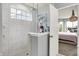 A stylish shower with glass doors and tile surround, complemented by a door to a bright, chandelier lit primary bedroom at 1071 Serenity Ct, Carmel, IN 46280