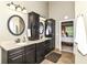 Bathroom with double sinks, dark cabinetry, and view of bedroom at 10888 Weston Dr, Carmel, IN 46032