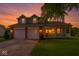 Charming two-story home featuring a front porch, attached two-car garage, and well-manicured lawn at sunset at 11612 E 75Th St, Indianapolis, IN 46236