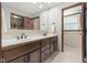 Bathroom vanity with double sink, wood cabinets, decorative mirror, and tiled backsplash at 11807 Rolling Springs Dr, Carmel, IN 46033
