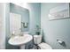 Stylish powder room with blue walls, pedestal sink, beach artwork, and toilet at 13163 N Departure W Blvd, Camby, IN 46113