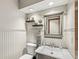 Clean half bath with a modern sink, decorative mirror, wainscotting, and wall-mounted shelves at 20322 Wagon Trail Dr, Noblesville, IN 46060
