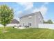 A grassy backyard with patio featuring grill, fire pit, and outdoor seating next to a privacy fence at 2260 Santa Fe Dr, Greenfield, IN 46140
