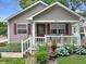 Close-up of front exterior with a cozy porch, white railing, red shutters, and beautifully landscaped garden at 2612 E Northgate St, Indianapolis, IN 46220