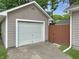 Garage with white door and tan siding, complemented by a wooden fence and green grass at 2612 E Northgate St, Indianapolis, IN 46220