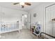 Neutral bedroom with a crib, open doorway to the bathroom, ceiling fan, and a stuffed bear wall decoration at 3030 E 236Th St, Cicero, IN 46034