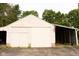 A garage with sliding doors and a covered side area flying an American flag, set against a backdrop of lush trees at 3431 W Mooresville Rd, Indianapolis, IN 46221