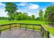 Backyard shot with a wooden deck overlooking a lush green field and trees on a partly cloudy day at 3512 N Wakeland Rd, Paragon, IN 46166