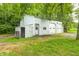View of the detached garage with two bay doors with a covered area and small door on a grassy lawn at 3512 N Wakeland Rd, Paragon, IN 46166
