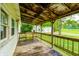 Exterior view of a covered porch with an aged floor and railing, looking to the backyard at 3512 N Wakeland Rd, Paragon, IN 46166